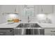 Close-up of a modern kitchen sink with stainless steel faucet, granite countertop and white cabinets at 112 Pointe Park Cir, Holly Springs, NC 27540
