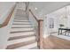 Elegant staircase with wood treads and white risers leading to an open doorway at 112 Pointe Park Cir, Holly Springs, NC 27540