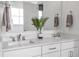 Bathroom vanity featuring double sinks, a large mirror, and a plant for added style at 112 Sire Ct, Holly Springs, NC 27540