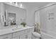 Bright bathroom featuring a white vanity, large mirror, and tub with white tile surround at 112 Sire Ct, Holly Springs, NC 27540
