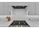Close-up of a gas range and hood in a modern white kitchen with white backsplash at 112 Sire Ct, Holly Springs, NC 27540