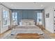 Bright main bedroom with a tufted headboard, a decorative blue accent wall, and wood flooring at 112 Sire Ct, Holly Springs, NC 27540