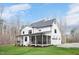 Rear view of a two-story white farmhouse featuring a large screened-in porch and well-maintained lawn at 1124 Westridge Rd, Rougemont, NC 27572
