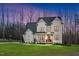 Charming two-story home featuring a covered porch with seating and a well-manicured lawn at twilight at 1124 Westridge Rd, Rougemont, NC 27572