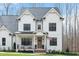 Beautiful two-story white farmhouse with covered porch, rocking chairs, and an American flag on display at 1124 Westridge Rd, Rougemont, NC 27572