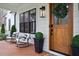 Close-up of a cozy front porch with rocking chairs, a wooden door with a wreath, and stylish outdoor decor at 1124 Westridge Rd, Rougemont, NC 27572