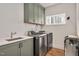 Modern laundry room features stainless steel washer and dryer, gray cabinets and a utility sink at 1124 Westridge Rd, Rougemont, NC 27572