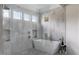 Elegant bathroom with white freestanding tub, marble-style walls, and natural light from multiple windows at 1421 Sky Vista Way, Raleigh, NC 27613