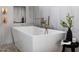 Close up on a free standing tub with bronze fixtures, marble-style tile, and a small decorative table at 1421 Sky Vista Way, Raleigh, NC 27613