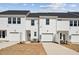 View of the side of newly constructed townhomes, each with a garage and matching white siding at 1426 Cooper St, Sanford, NC 27330