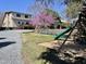 Large backyard with a wooden playset and a blooming tree, set against a two-story home with a deck at 1426 N Roxboro St, Durham, NC 27701