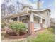 Side exterior showcasing the covered porch, brick pillars, and established landscaping, highlighting the home's charm at 1426 N Roxboro St, Durham, NC 27701