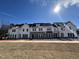 New townhomes featuring a mixture of siding and stone, snow dusted rooftops, and newly landscaped yards at 1430 Cooper St, Sanford, NC 27330