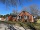 Side view of a charming red brick house with black shutters and well maintained lawn and landscaping at 148 Baptist Church Rd, Henderson, NC 27537