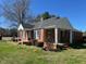 Side view of a charming red brick house with black shutters and well maintained lawn and landscaping at 148 Baptist Church Rd, Henderson, NC 27537