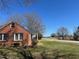 Side view of a red brick home with a covered porch and a well-maintained lawn at 148 Baptist Church Rd, Henderson, NC 27537