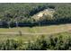 Scenic aerial view of wooded acreage with power lines, a creek, and distant house with equestrian arena at 195 Falcon Ln, Rougemont, NC 27572