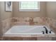 A relaxing soaking tub sits beneath a window offering natural light in this neutral toned bathroom at 195 Falcon Ln, Rougemont, NC 27572