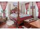 A four-poster bed sits in the primary bedroom, offering two windows and neutral walls with hardwood floors at 195 Falcon Ln, Rougemont, NC 27572