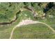 Aerial shot of a winding creek flowing through a lush, green landscape with mature trees at 195 Falcon Ln, Rougemont, NC 27572
