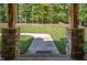 View of the green lawn through the pillars of the home's porch, framed by stone and greenery at 195 Falcon Ln, Rougemont, NC 27572