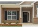 Charming brick home entrance featuring a black front door, large window, and well-maintained landscaping at 210 Cason Dr, Gibsonville, NC 27249