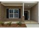 Inviting front porch with brick accents, black shutters, and a welcoming entry door at 210 Cason Dr, Gibsonville, NC 27249