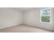 A bright bedroom has neutral carpet, white walls, and a window with a view to the outdoors at 269 Umstead St, Sanford, NC 27330