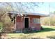 Outdoor shed with a door and window surrounded by blossoming branches, adding a touch of nature at 2984 Ashe Ave, Dunn, NC 28334