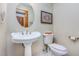 Compact half bathroom features a pedestal sink, toilet, and wall decor at 3101 Rutledge Ct, Raleigh, NC 27613