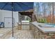 Stone clad outdoor kitchen with stainless grill, grey countertops and shade umbrella at 3548 Willow Green Dr, Apex, NC 27502