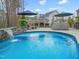 A waterfall spills into this beautiful inground pool, with nearby fireplace and patio furniture at 3548 Willow Green Dr, Apex, NC 27502