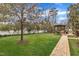 A spacious backyard with green lawn, a playground, a wooden patio, and a walkway surrounded by a white fence at 601 Ballad Creek Ct, Cary, NC 27519