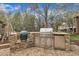 Outdoor kitchen featuring stainless steel grill, smoker, refrigerator, and stone surround at 601 Ballad Creek Ct, Cary, NC 27519