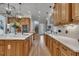 An open kitchen with an island and stone countertops, wood cabinets, and a view of the staircase at 601 Ballad Creek Ct, Cary, NC 27519