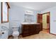 Light blue bathroom with wood vanity, tile floor, and natural light at 651 Sagamore Dr, Louisburg, NC 27549