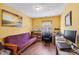 Cozy bedroom with a purple futon, wooden floors, and a brightly lit workspace with computer at 6923 Fox Haven Pl, Raleigh, NC 27616