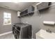 Modern laundry room featuring a stainless steel washer and dryer, storage shelves, and utility sink at 709 Teal Lake Dr, Holly Springs, NC 27540