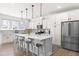 Bright kitchen boasts white cabinets, quartz countertops, stainless steel appliances, and a large center island at 74 Silver Moon Ln, Clayton, NC 27527