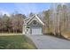 Two-story garage with a white garage door and door, exterior green siding, and large driveway at 1001 Hazeltown Rd, Wake Forest, NC 27587