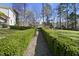 A backyard garden pathway lined with manicured hedgerows leading to an outdoor seating area with views of a house at 1006 Henny Pl, Raleigh, NC 27614