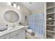 Bright bathroom with white vanity, open shelving, and a blue patterned shower curtain at 1006 Henny Pl, Raleigh, NC 27614