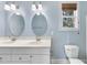 Bright bathroom featuring double vanity, oval mirrors, and a window letting in natural light at 1006 Henny Pl, Raleigh, NC 27614