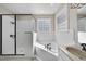 Corner soaking tub with black trim and glass block window, in a white tiled bathroom at 1006 Henny Pl, Raleigh, NC 27614