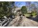 An outdoor stone patio includes a stone firepit and Adirondack chairs, nestled in a backyard garden with mature trees at 1006 Henny Pl, Raleigh, NC 27614