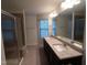 Bright bathroom featuring granite countertop with double sinks, walk-in shower, and window over tub at 1022 Azimuth Dr, Durham, NC 27713