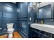 Stylish powder room with blue paneled walls, elegant fixtures, modern sink, and warm wood floors at 10726 Trego Trl, Raleigh, NC 27614