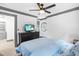 Bright bedroom featuring a blue bed, a television, a ceiling fan, and two windows for natural light at 10726 Trego Trl, Raleigh, NC 27614