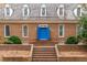 A welcoming brick home with a striking blue double-door entry, steps and mature greenery provides classic curb appeal at 10726 Trego Trl, Raleigh, NC 27614