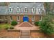 Aerial shot of a brick home featuring a detailed roof, dormer windows, and brick stairs leading up to a blue door at 10726 Trego Trl, Raleigh, NC 27614